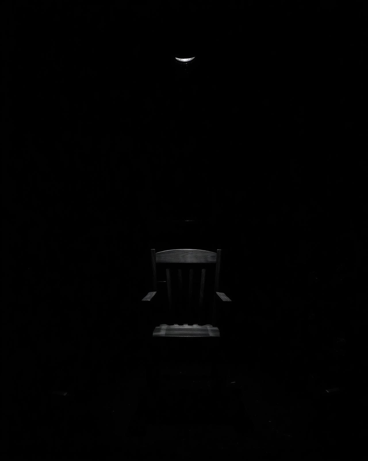 Lone wooden chair lit by a single spotlight